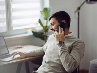 Unternehmer telefoniert und macht gleichzeitig Zahlungen am Laptop